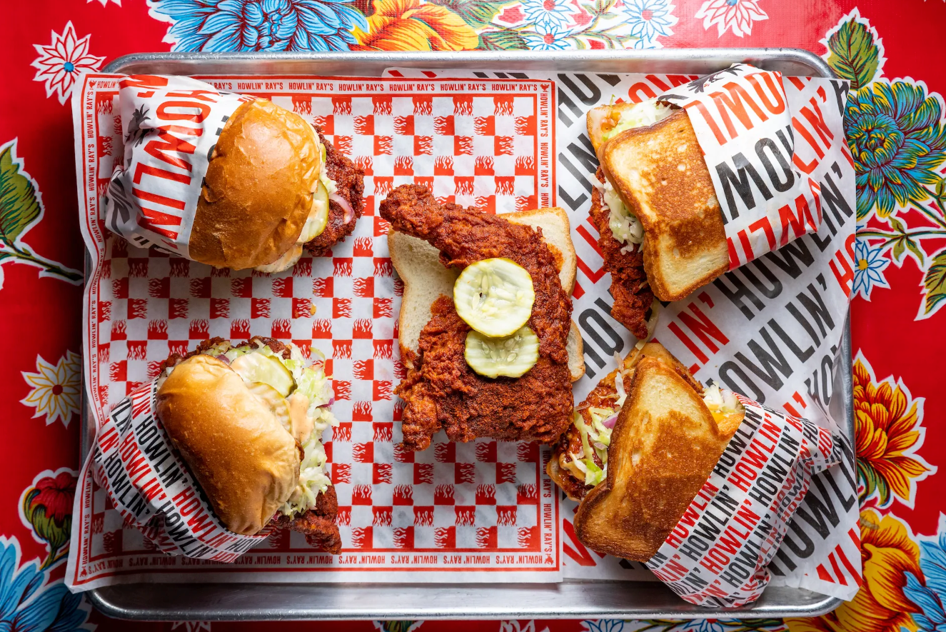 Sandwiches and more from Howlin’s Ray’s on a colorful table.